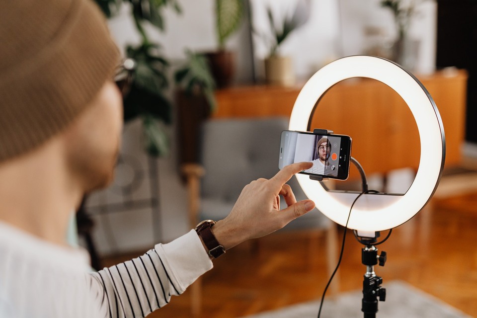 A person recording themselves with a smartphone using a ring light