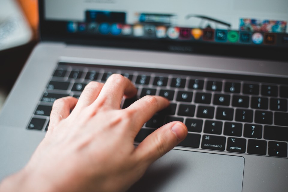 A close-up of a hand typing on a laptop keyboard