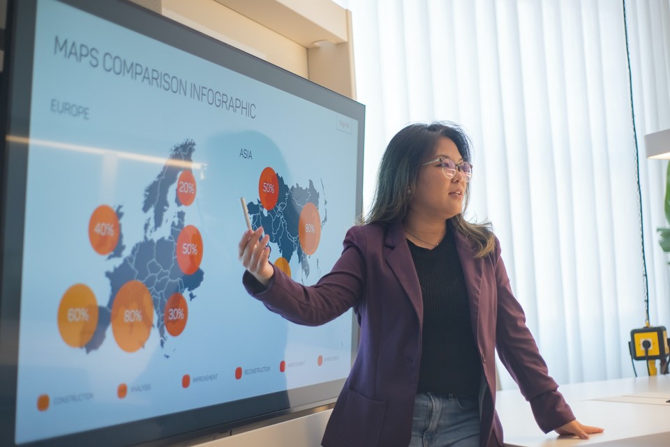 Woman presenting a PPT on a large screen in an office setting