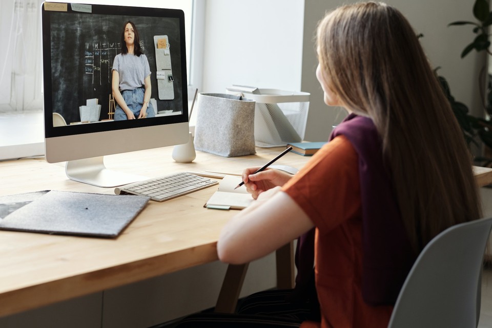 A woman taking notes while viewing an AI-generated video on a computer