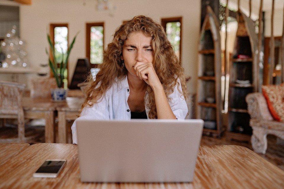 A woman with curly hair, wearing a white shirt, looking puzzled thinking what makes a video viral