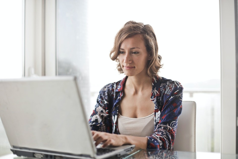 Woman working on a laptop at a bright, window-lit space