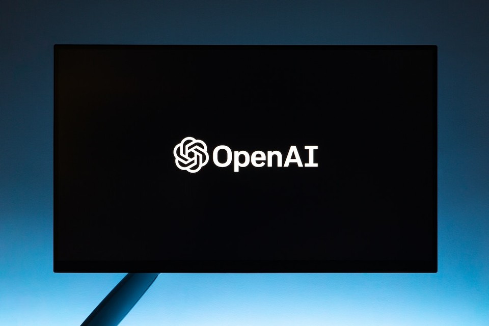 Computer monitor displaying the OpenAI logo on a dark background